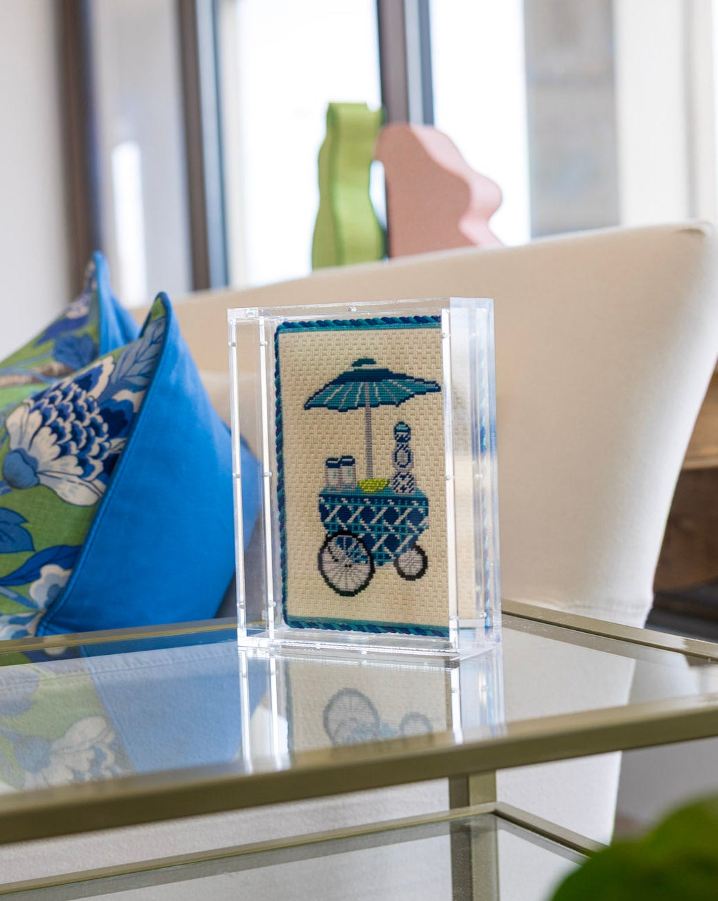Decorative item with a design of a baby carriage and umbrella on a glass shelf.