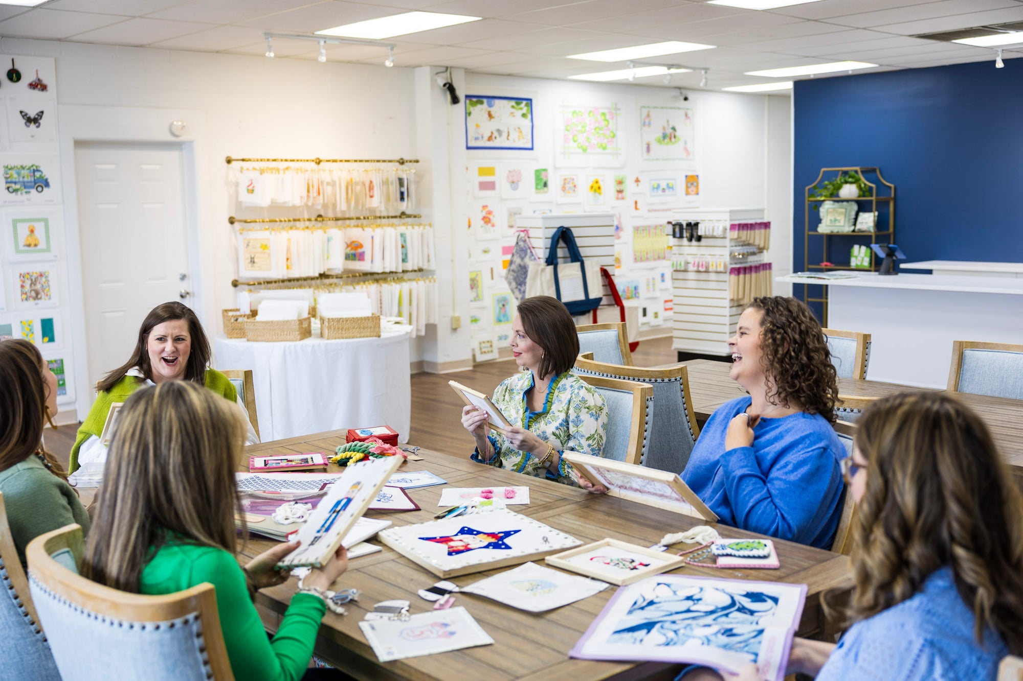 Group of people sitting around a table in a room with art supplies and decor.