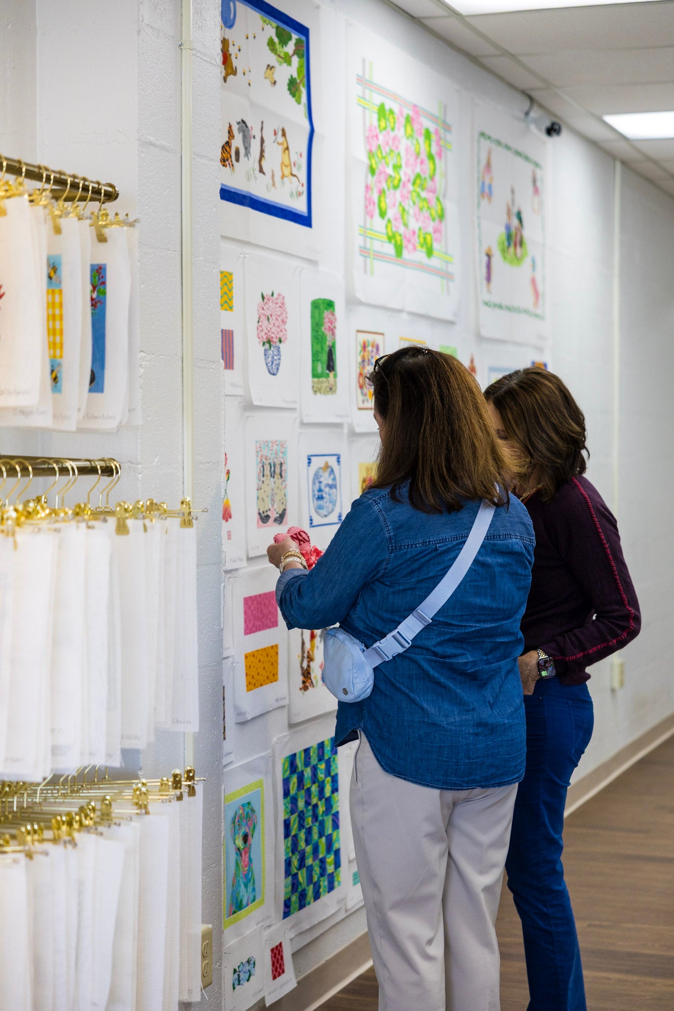 Two women looking at canvases on a wall.