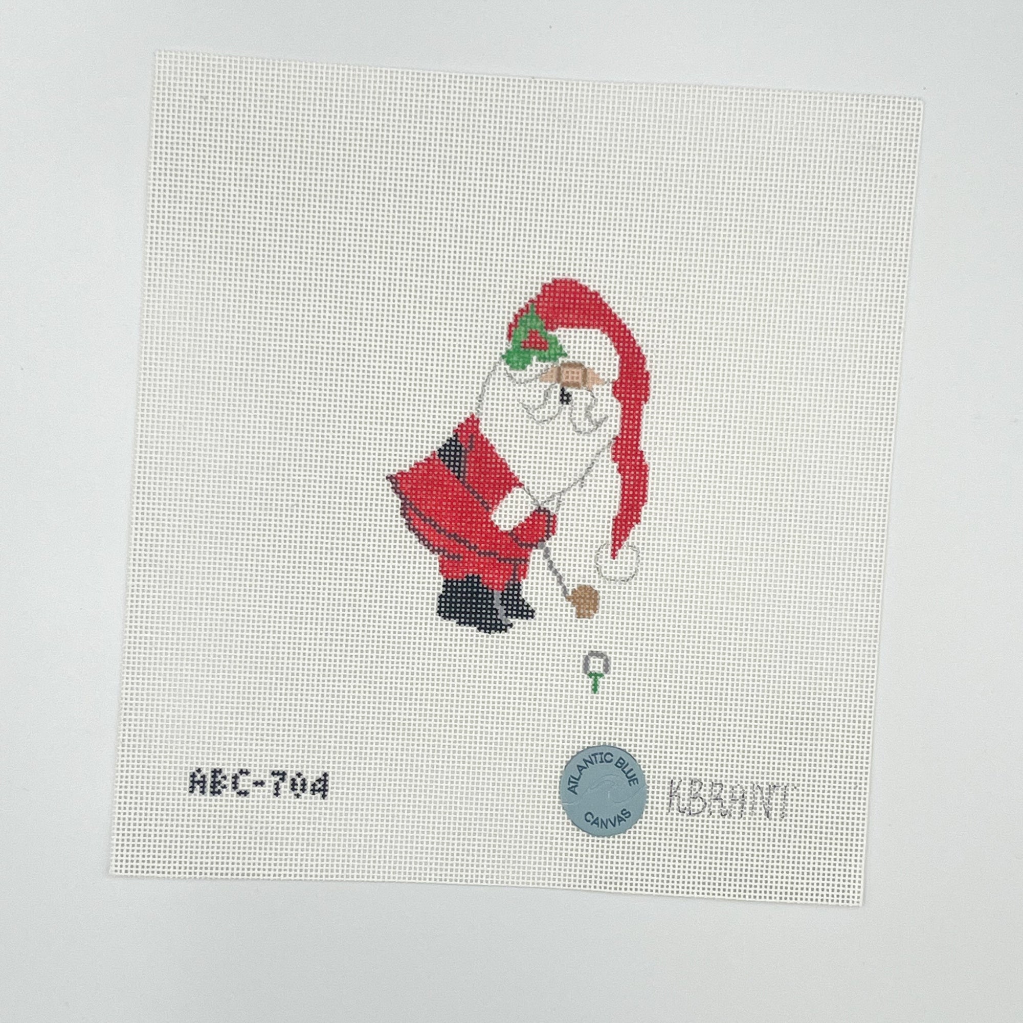 Needlepoint canvas with red santa hitting a golf ball on a white background